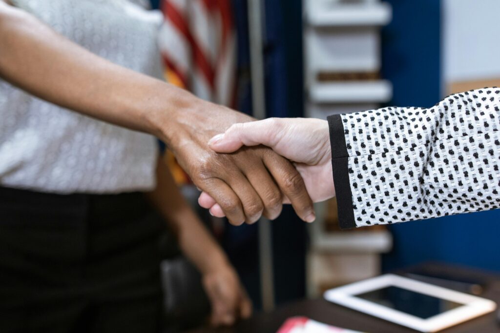 Close-up of two professionals shaking hands in a business environment.