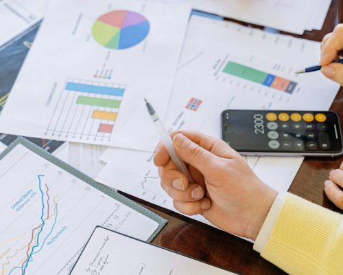 A close-up of businesspeople analyzing financial data and charts during a meeting.