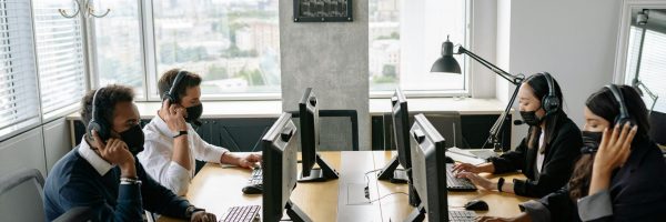 Professional team in a modern call center working collaboratively with headsets and computers.